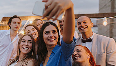 Eine Gruppe an Menschen machen in Feierlaune ein Selfie auf der Terrasse. (c) AleksandarNakic